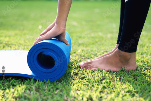 close up woman rolling yoga mat after working out at park