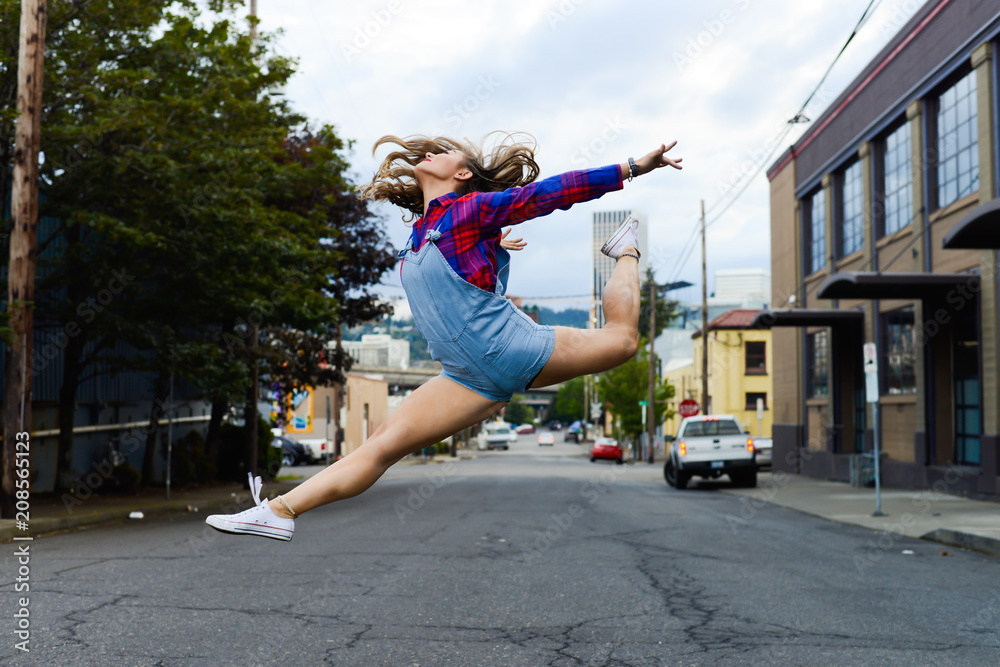 Dancing girl leaping in air in city street