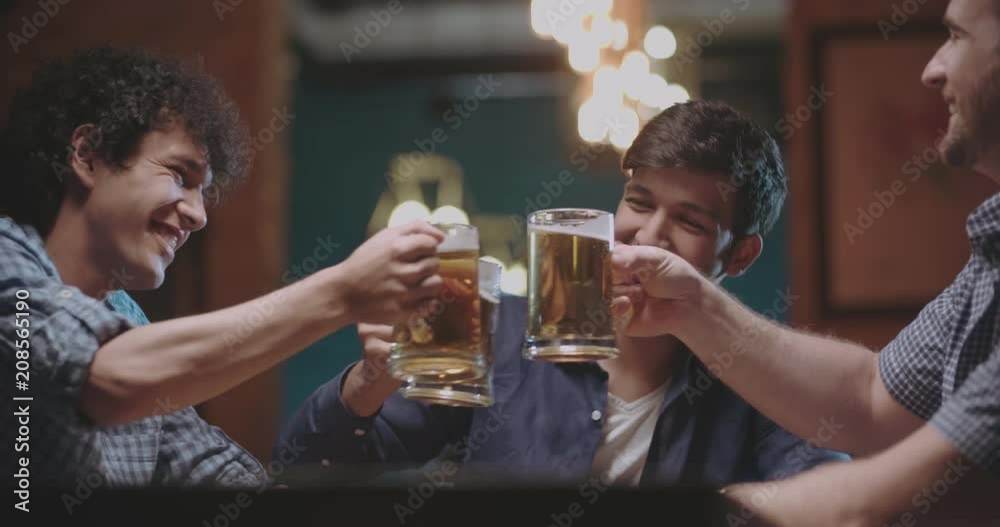 three young friends drinking beer in bar or pub 4k dollyshot