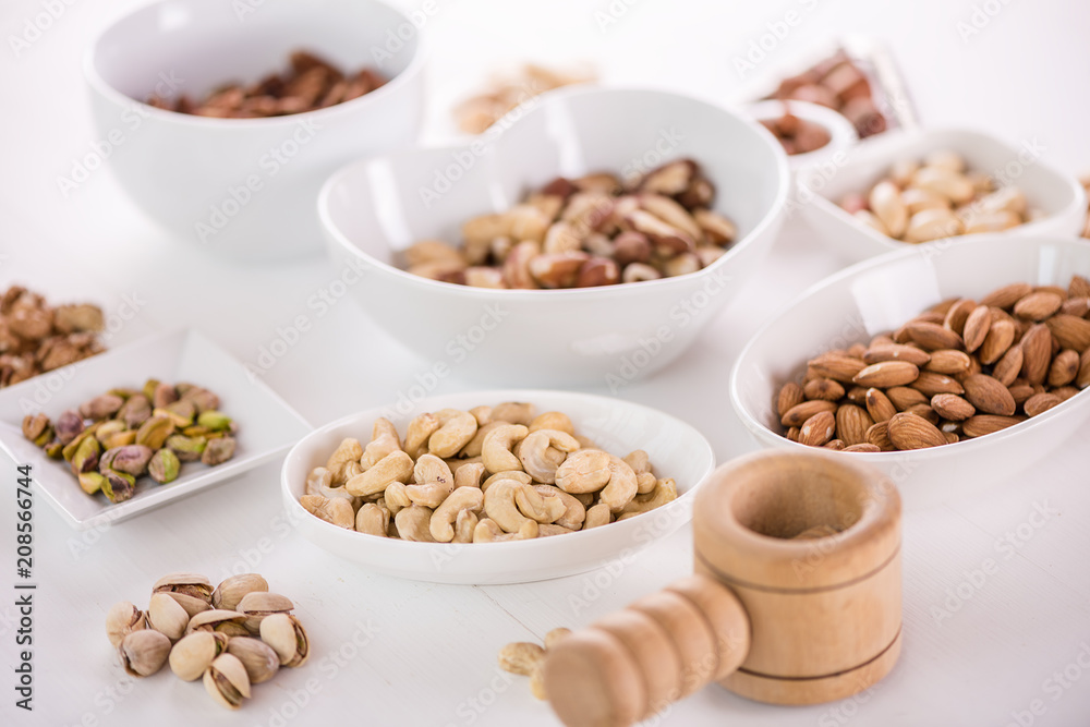 variety, mixture of different nuts on white background in white bowls variety, mixture of different nuts on white background in white bowls