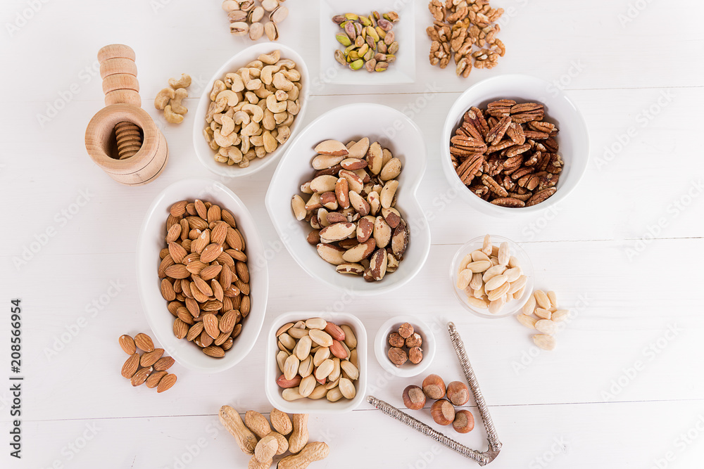 variety, mixture of different nuts on white background in white bowls variety, mixture of different nuts on white background in white bowls