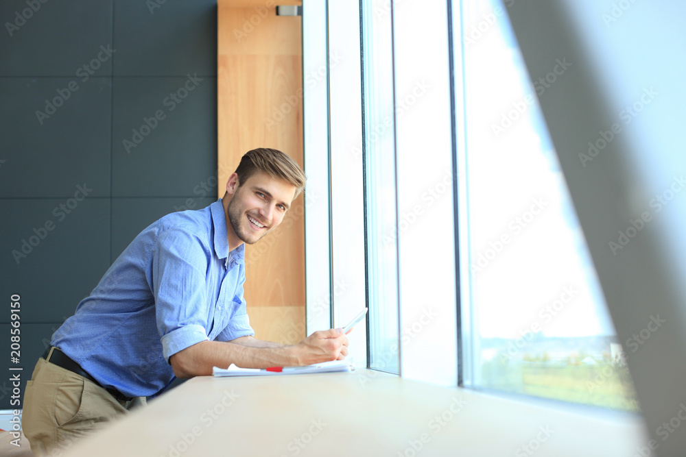 Portrait of young man using tablet in office.