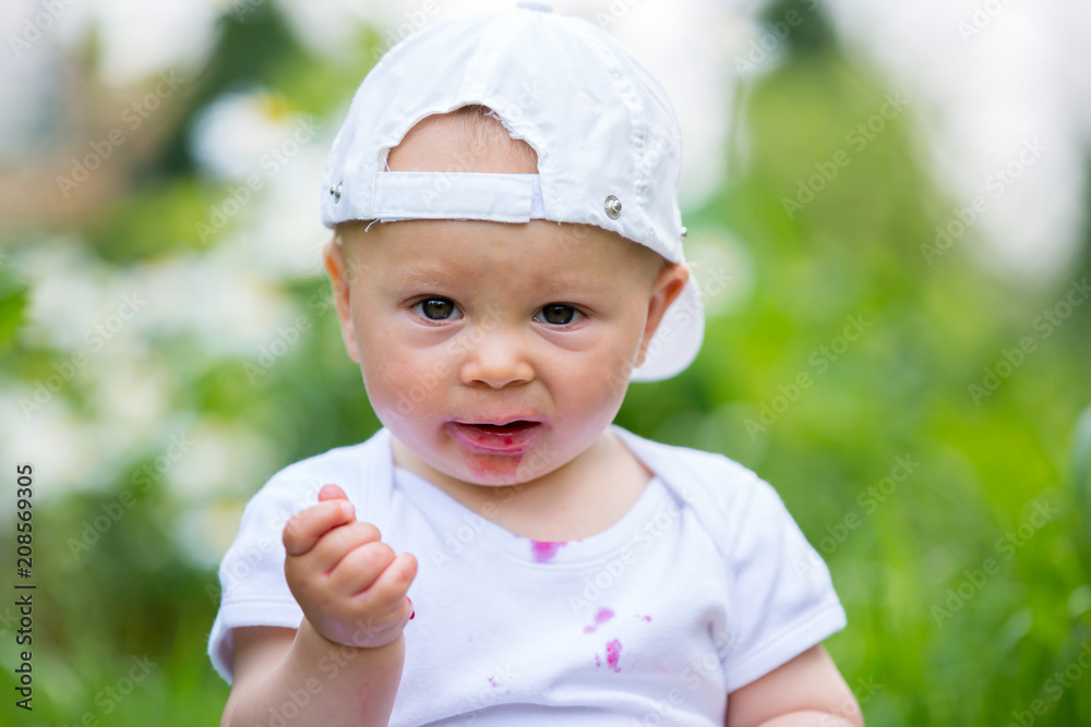 Sweet little child, baby boy, eating cherries in garden, enjoying tasty fruit Sweet little child, baby boy, eating cherries in garden, enjoying tasty fruit