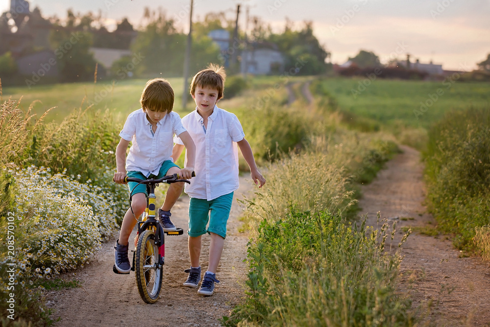 Sporty children, boy brothers, riding bikes on a rural landscape together