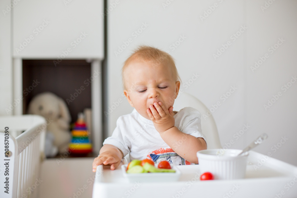 Sweet baby child, boy, eating mashed food and fresh vegetables, sitting in high baby chair Sweet baby child, boy, eating mashed food and fresh vegetables, sitting in high baby chair