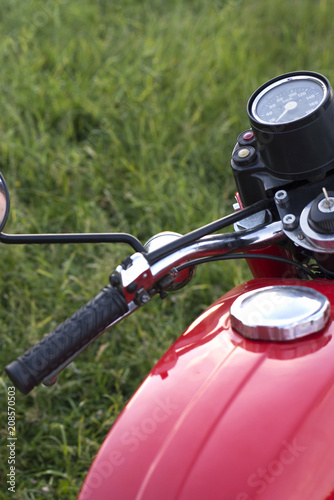 Part of a restored vintage motorcycle against a grass background © Pavlo