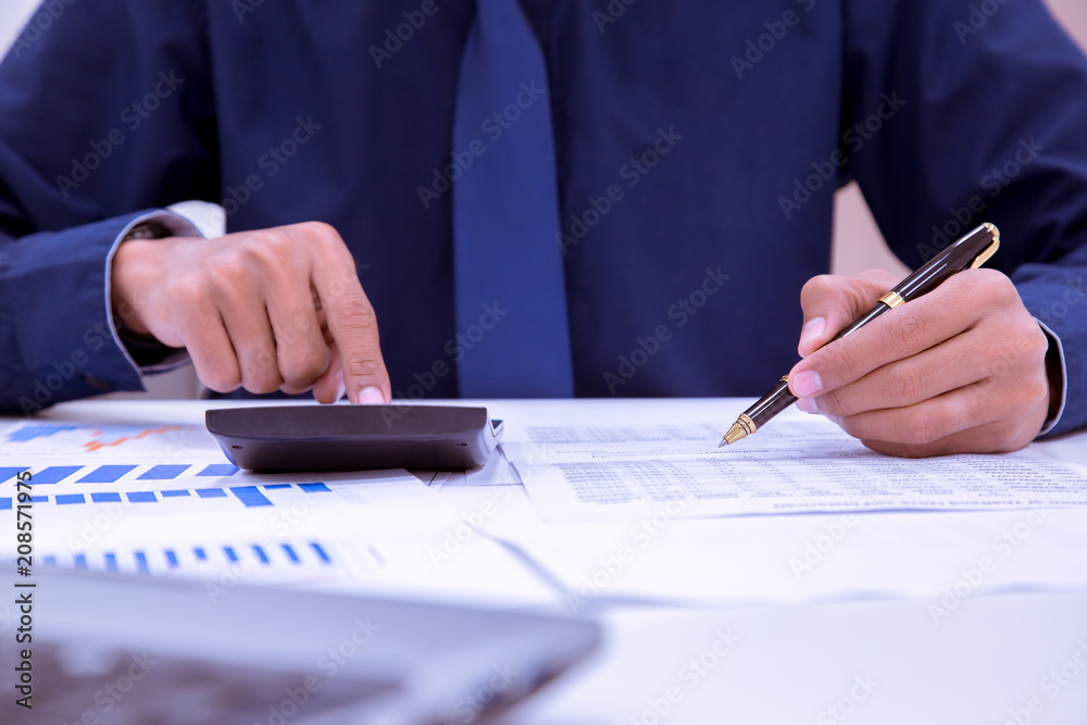 Asian male accountants or bankers perform calculations. Financial savings and economic ideas for 2018 through laptops in the office. Asian male accountants or bankers perform calculations. Financial savings and economic ideas for 2018 through laptops in the office.