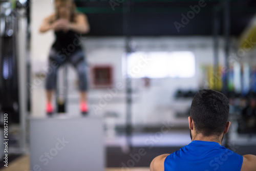 woman working out with personal trainer jumping on fit box