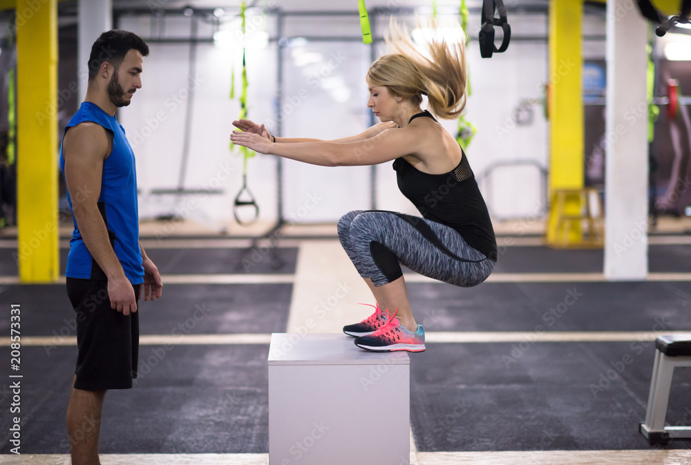 Obraz premium woman working out with personal trainer jumping on fit box