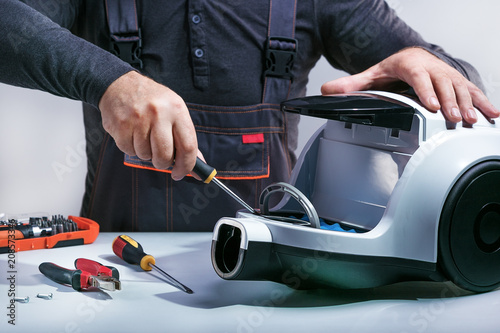 Repairman repairs of vacuum cleaner. Repairing cleaner.Small business. photo