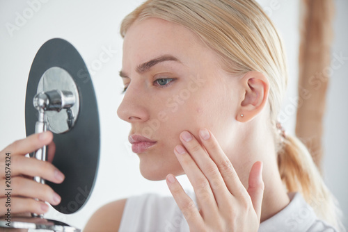 Skin problems. Girl looking in the mirror