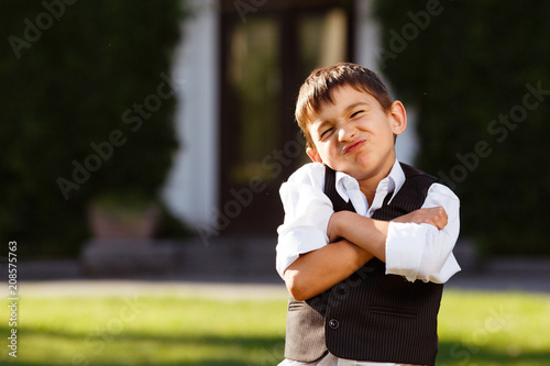 Cheerful boy in fashionable suit on green grass