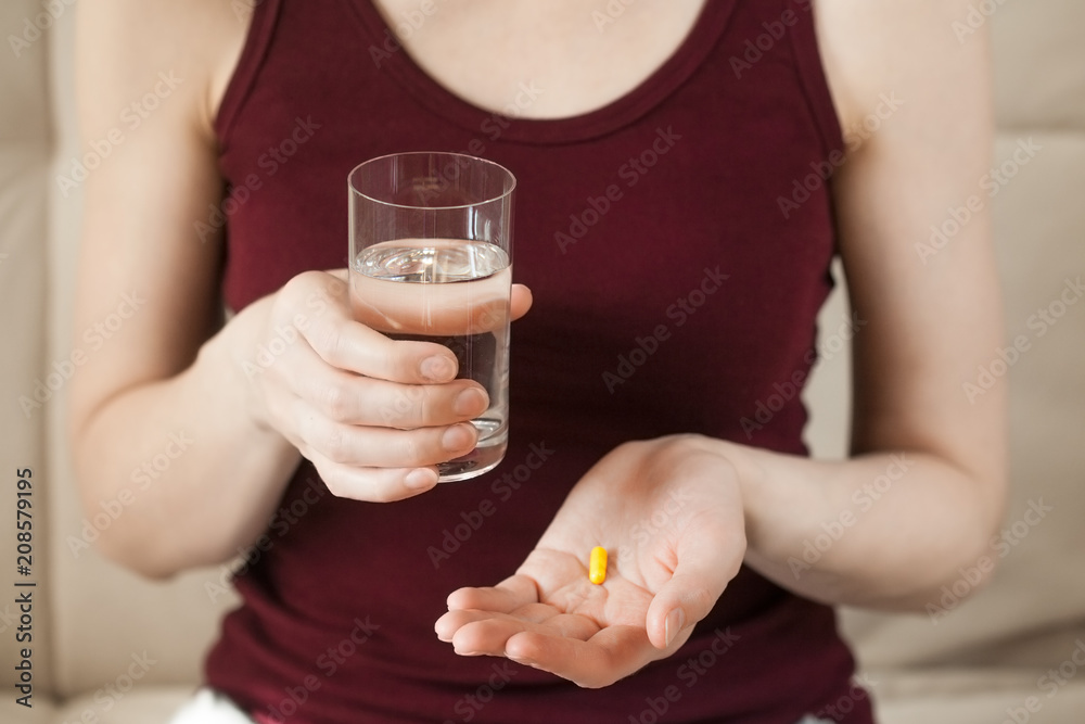 young woman holding pill and glass of water young woman holding pill and glass of water