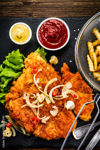 Fried pork chop, French fries and vegetable salad photo