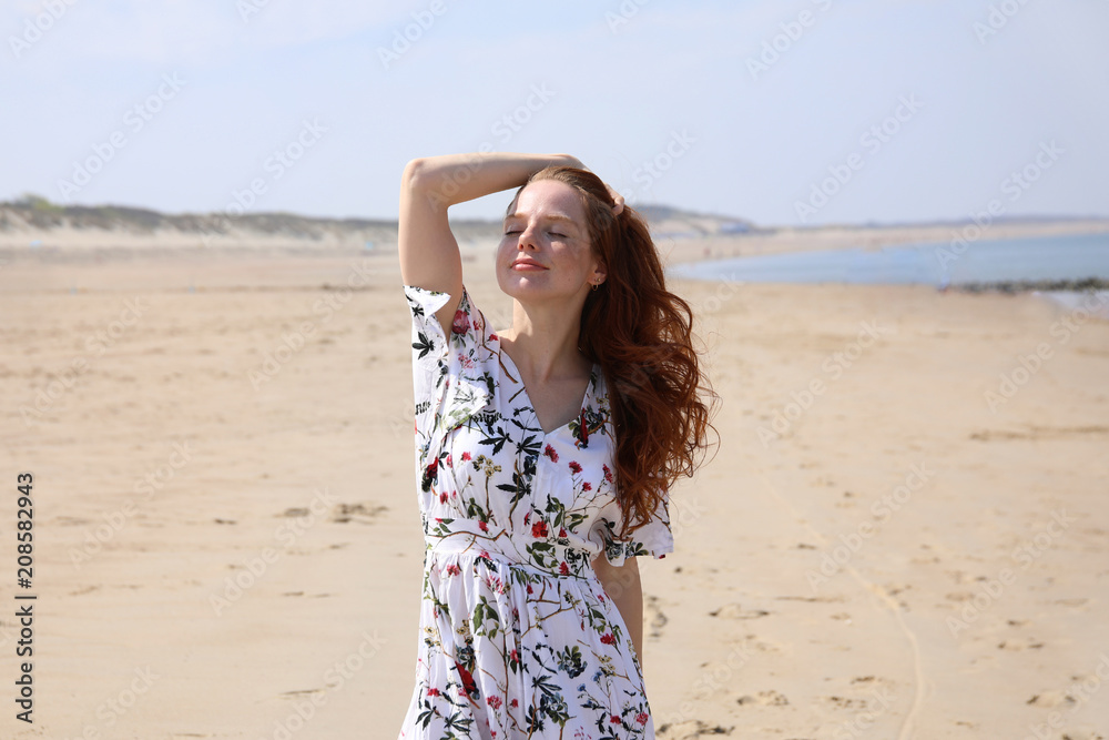 Hübsche rothaarige Frau steht mit geschlossenen Augen an einem Strand Hübsche rothaarige Frau steht mit geschlossenen Augen an einem Strand