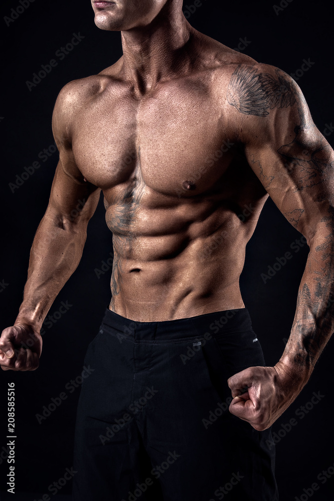 Unrecognizable Strong bodybuilder with six pack. Bodybuilder man with  perfect abs, shoulders,biceps, triceps and chest, personal fitness trainer  flexing his muscles ob black, dark background in studio Stock Photo | Adobe  Stock