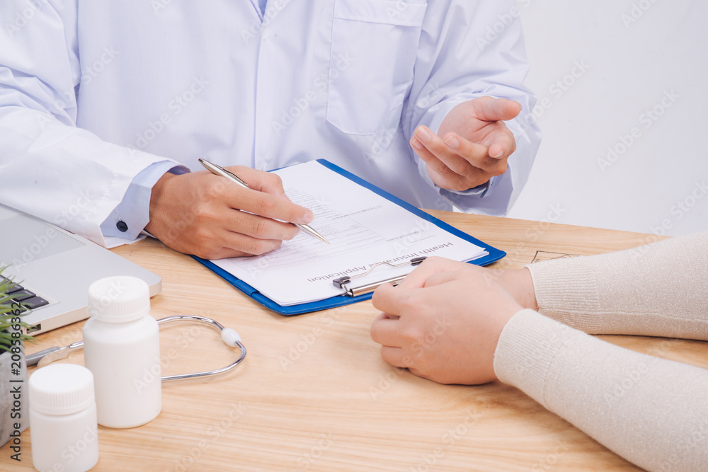 Doctor hand holding pen writing patient history list on note pad and talking to the patient about medication and treatment. Doctor hand holding pen writing patient history list on note pad and talking to the patient about medication and treatment.
