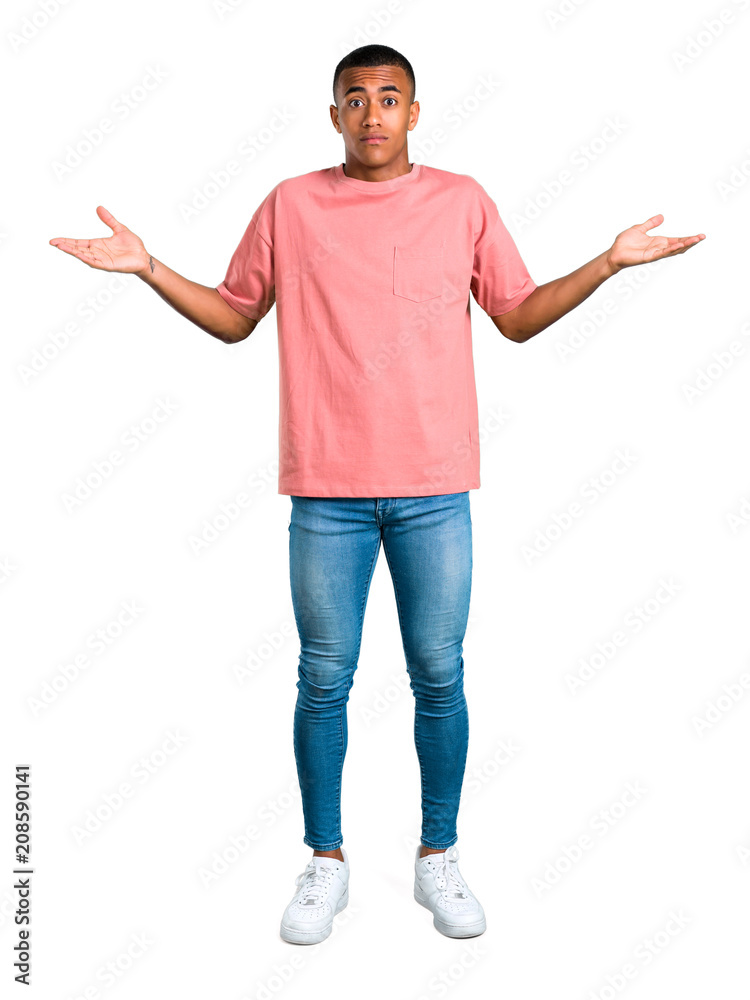 Standing young african american man having doubts and with confuse face expression while raising hands and shoulders on isolated white background Standing young african american man having doubts and with confuse face expression while raising hands and shoulders on isolated white background