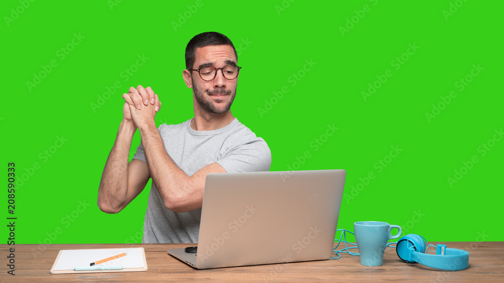 Confident young man sitting at his desk with a gesture of teamwork - Green background Confident young man sitting at his desk with a gesture of teamwork - Green background
