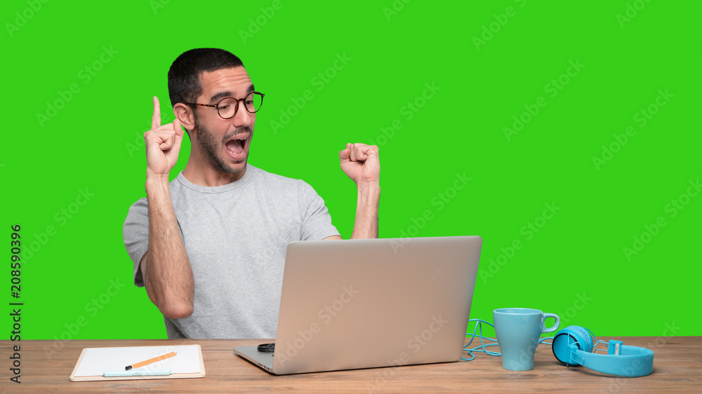 Happy young man sitting at his desk and doing a gesture of number one - Green background Happy young man sitting at his desk and doing a gesture of number one - Green background
