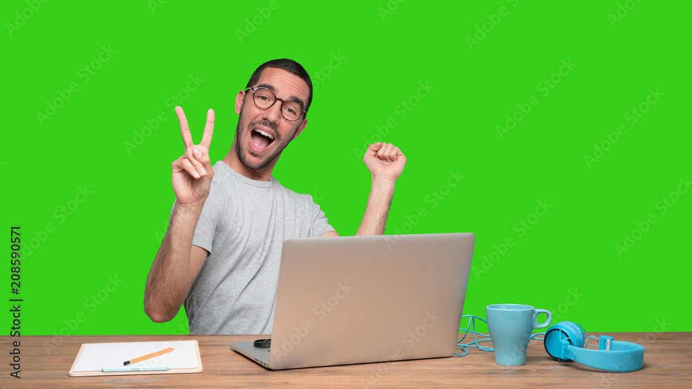Winner young man sitting at his desk - Green background Winner young man sitting at his desk - Green background