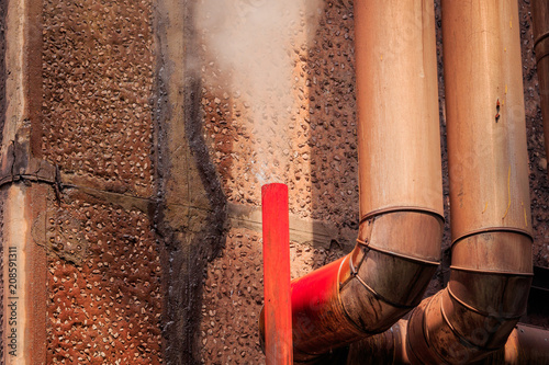Hot condensed water vapor gushing from the red pipe outside the factory building