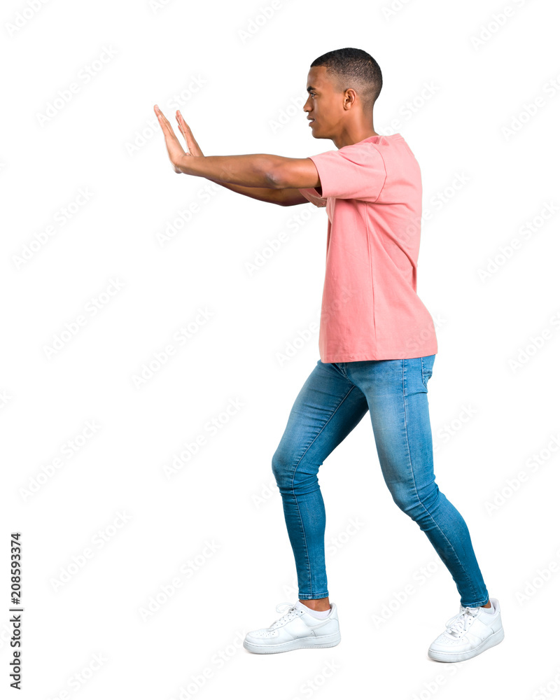 Standing young african american man pushing something on isolated white background Standing young african american man pushing something on isolated white background