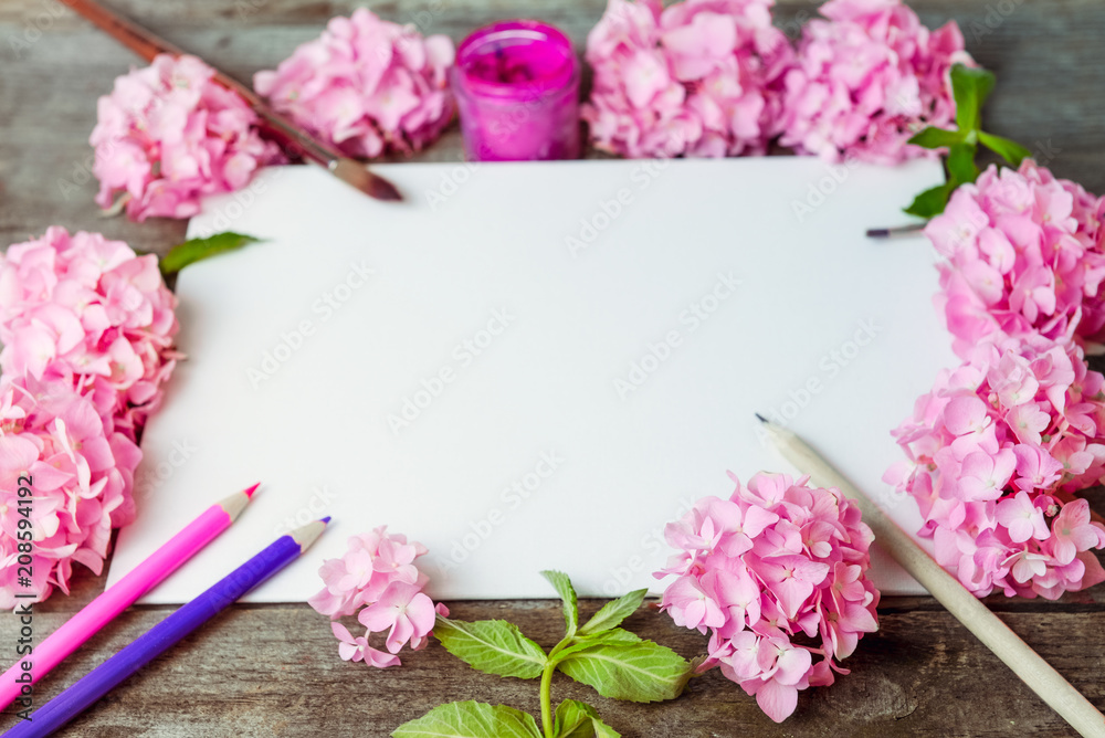 Close up creative layout made of pink wisteria flowers, canvas blank, brushes, fuchsia color gouache paint, color pencils on the old wooden rustic table. Art concept. Selective focus. Copy space.