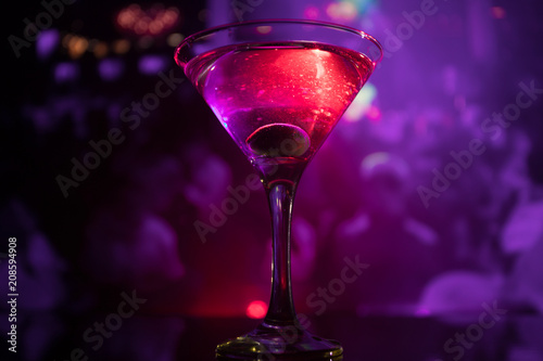 glass with martini with olive inside. Close up view of glass with club drink on dark foggy toned background. Club drink concept