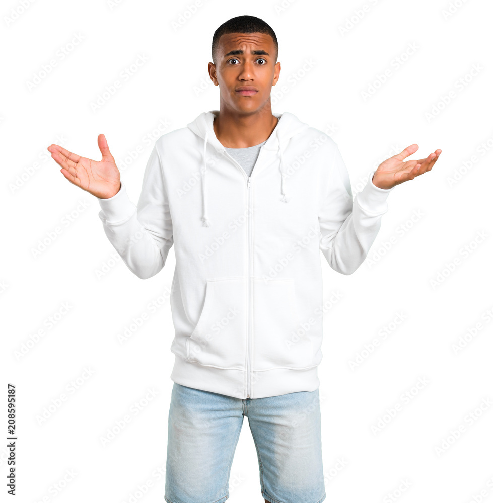 Dark-skinned young man with white sweatshirt having doubts and with confuse face expression while raising hands and shoulders Uncertain concept on isolated white background Dark-skinned young man with white sweatshirt having doubts and with confuse face expression while raising hands and shoulders Uncertain concept on isolated white background