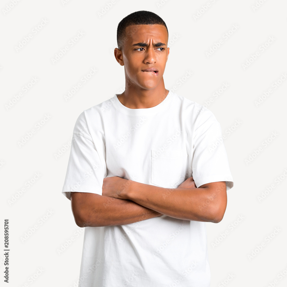 Young african american man having doubts and with confuse face expression while bites lip. Questioning an idea on isolated background Young african american man having doubts and with confuse face expression while bites lip. Questioning an idea on isolated background