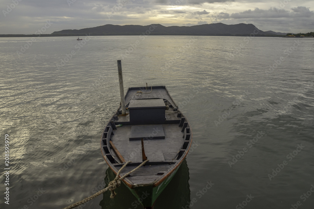 Small boat tied the rope at the seaside, morning sun