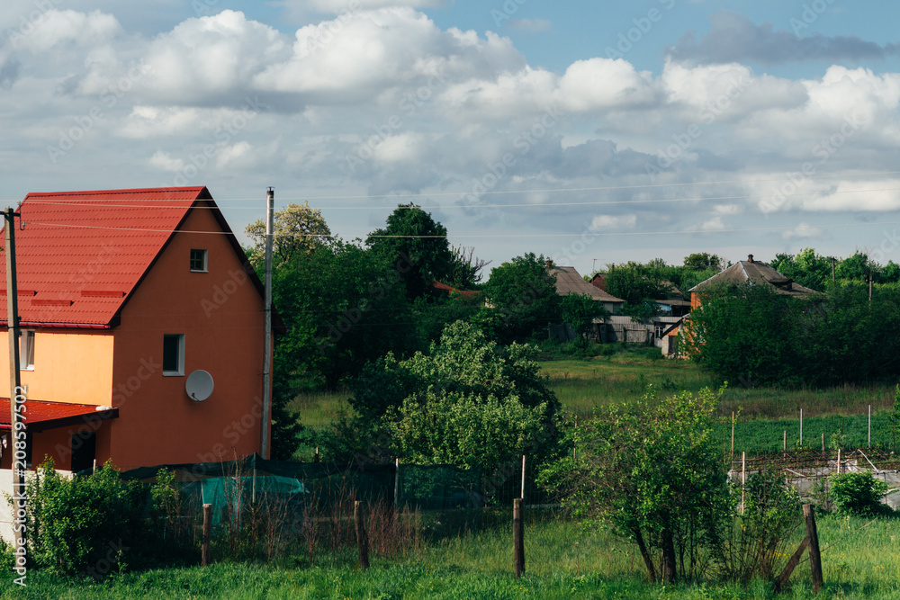 Cumulus clouds over a village in the Black Forest. orange house with a red roof