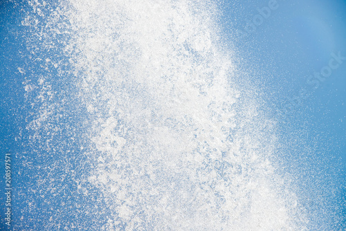 Strong flow of water on blue sky background, closeup