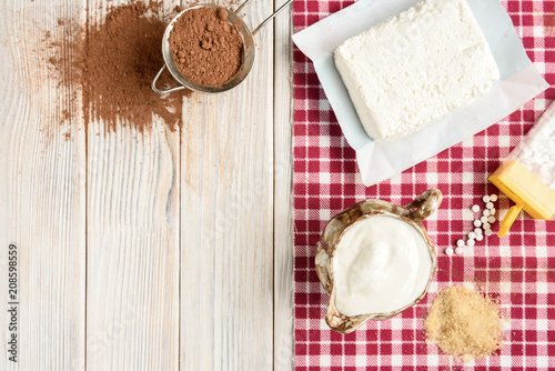 Ingredients for homemade cottage cheese souffle dessert with cocoa on white wooden table. Recipe of healthy dessert.