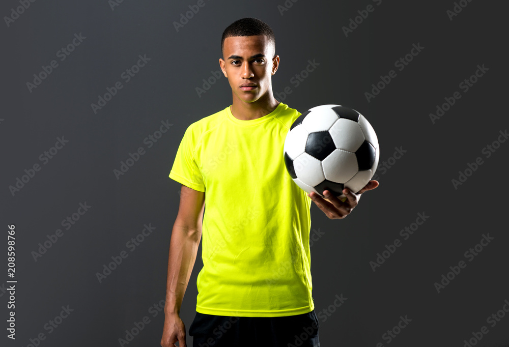 Soccer player man with dark skinned playing catching a ball with his hands on dark background Soccer player man with dark skinned playing catching a ball with his hands on dark background
