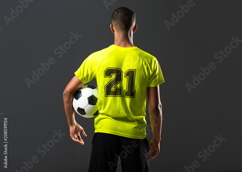 Soccer player man with dark skinned playing catching a ball with his hands on dark background