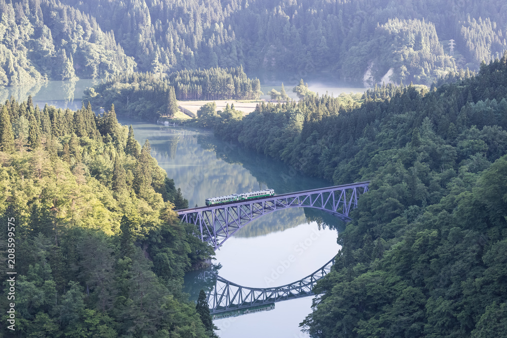 Fototapeta premium Fukushima, JAPAN - June 17 : The local train Tadami line and Tadami river on June 17 , 2017 in Fukushima , Japan. This train services in East Japan railway company's Tadami line.