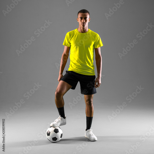 Soccer player man with dark skinned playing on dark background © luismolinero