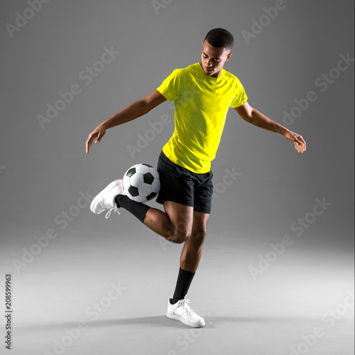 Fototapeta Naklejka Na Ścianę i Meble -  Soccer player man with dark skinned playing on dark background