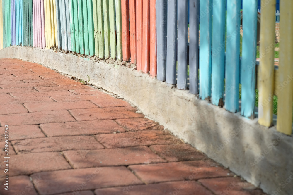 Colorful wood fence on the red brick walkway Colorful wood fence on the red brick walkway