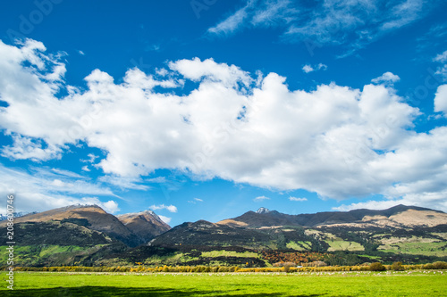 Beautiful scene of the green grassland and alps mountain with cloudy sky. © Klanarong Chitmung