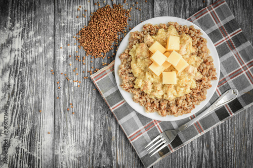 Chicken gravy with buckwheat porridge and cheese on white plate on grey wooden background. Healthy dinner. photo