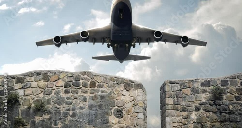 A jumbo jet taking off from behind a stone wall