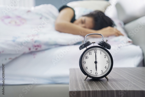 Alarm clock with young woman in the bedroom
