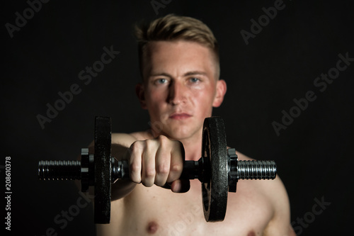 Fototapeta Naklejka Na Ścianę i Meble -  Gym and dumbbells. Young attractive guy. Black background. 
