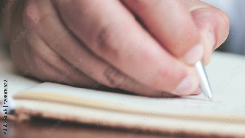 close up a hands writing on the diary book in living room