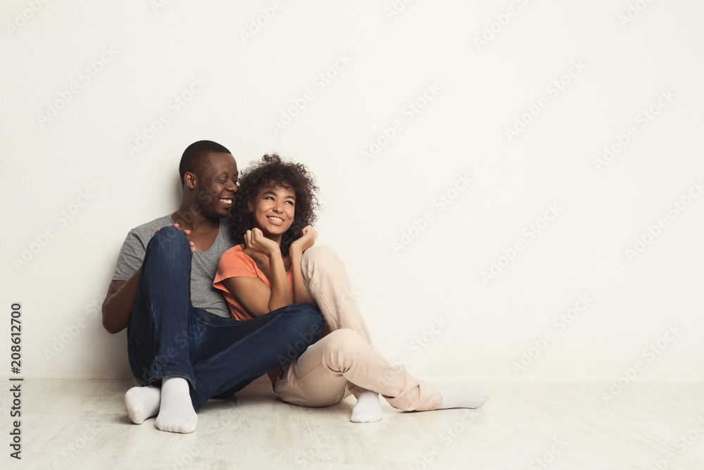 African-american couple hugging, sitting on floor African-american couple hugging, sitting on floor