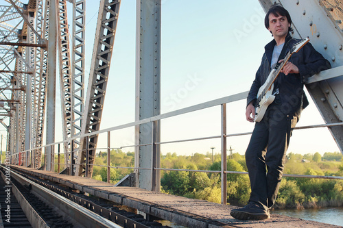 Man with an electric guitar in the industrial landscape outdoors