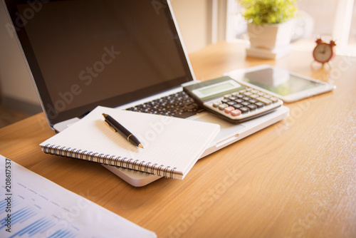 Laptop, coffee cup with financial documents on wooden table